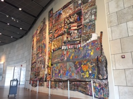 An enormous mural made of textiles by Aminah Brenda Lynn Robinson fills a wall at the National Underground Railroad Freedom Center